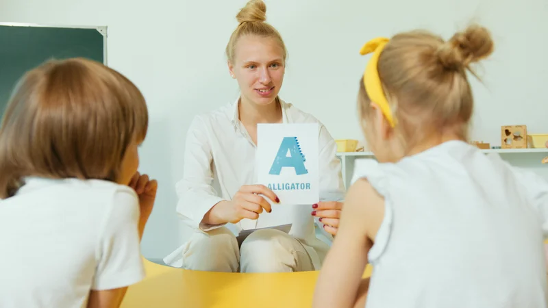 Teacher showing alphabet flashcards to young students during phonics lesson