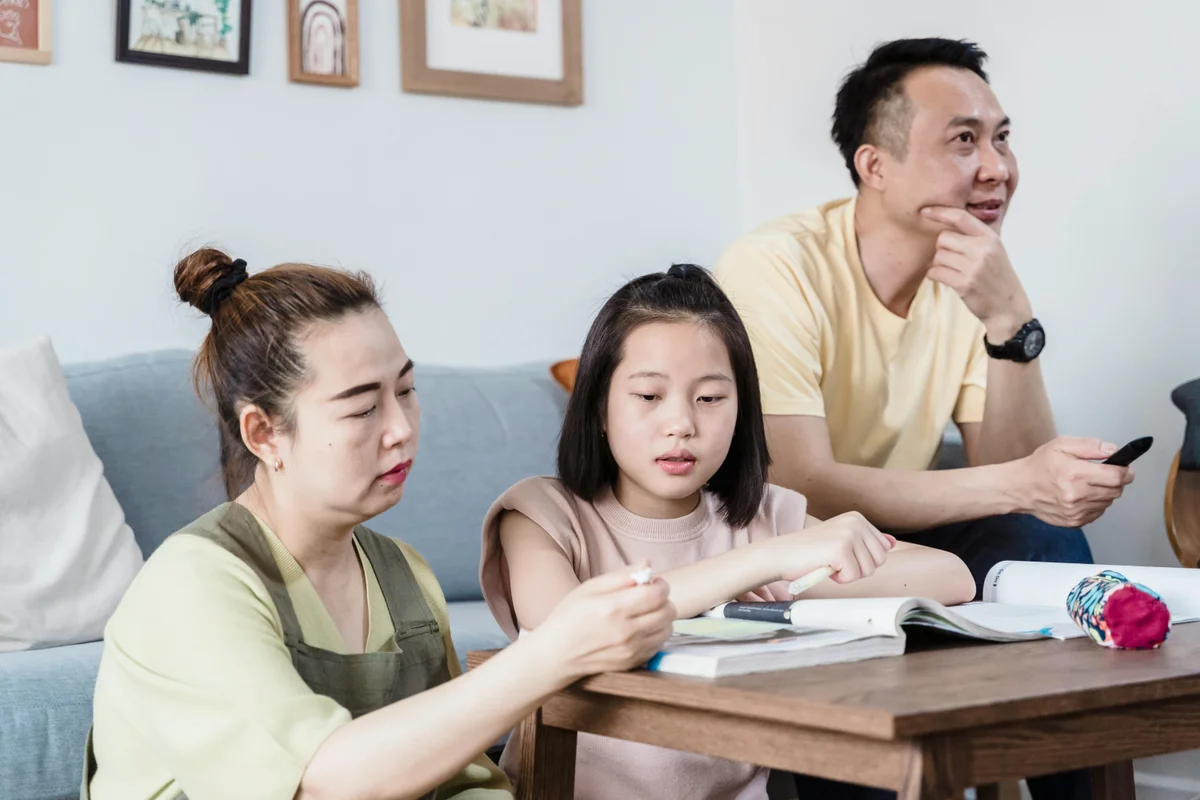 Family helping daughter with homeschool lessons at home