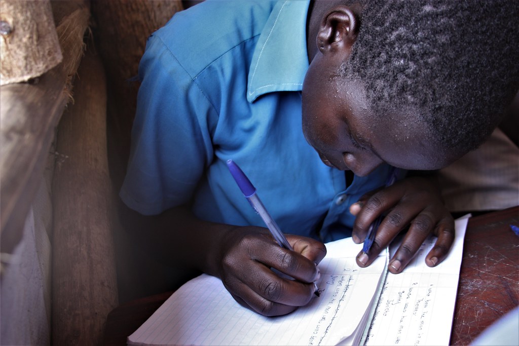 Child writing in notebook practicing grammar editing skills