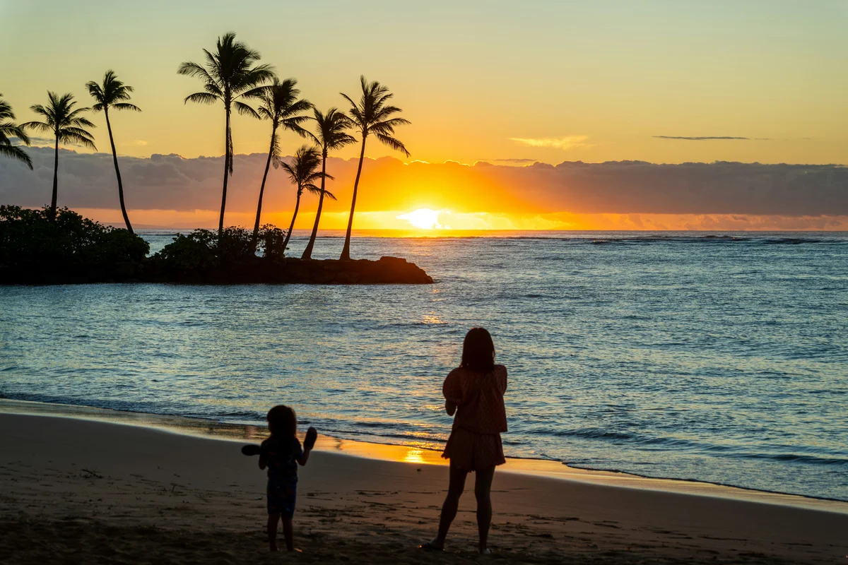 Mother and child enjoying outdoor learning time on a Hawaiian beach at sunset