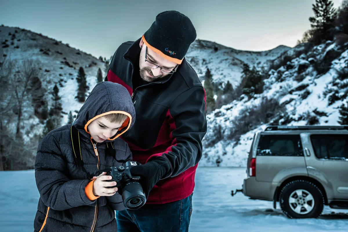 Father teaching son in the Alaska wilderness with snow-covered mountains