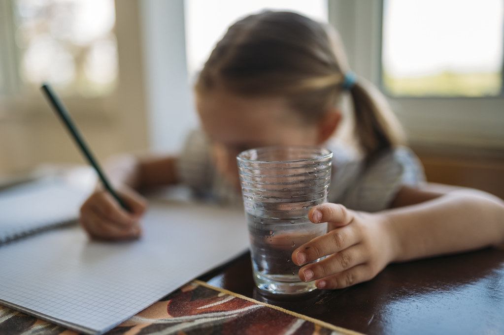 Child writing in notebook with relaxed expression