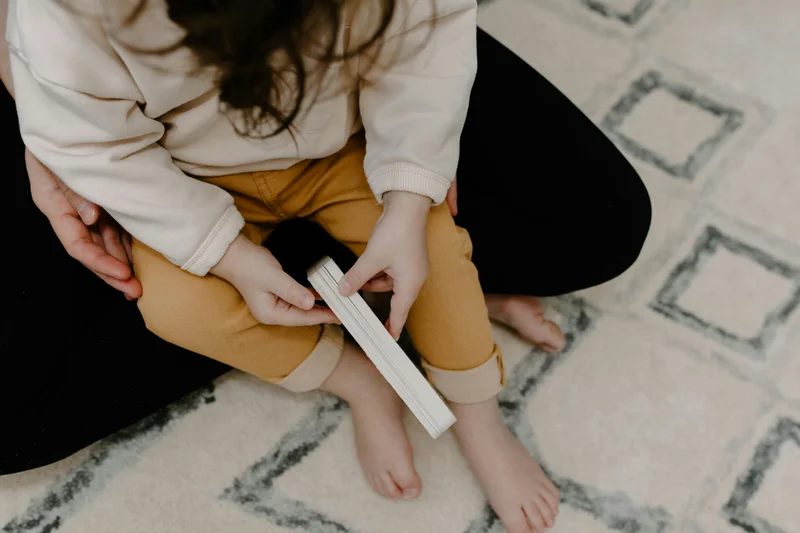 Parent helping child read a book during homeschool lesson