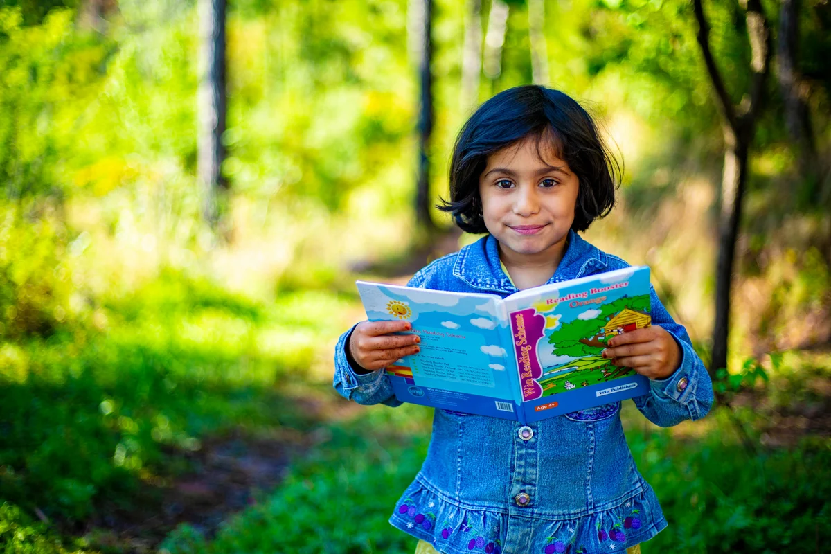 Child reading a living book outdoors - Charlotte Mason method homeschooling